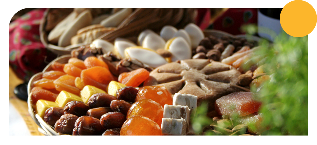 a traditional Provençal Christmas dessert display known as the 13 desserts, arranged on a woven tray.
It features dried fruits, nuts, nougat, candied fruits and a pompe à l’huile, symbolizing sharing and abundance during the Christmas season