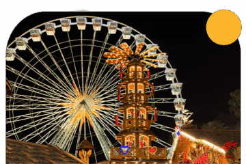 La grande roue de nuit avec la tour du marché de Noël devant.